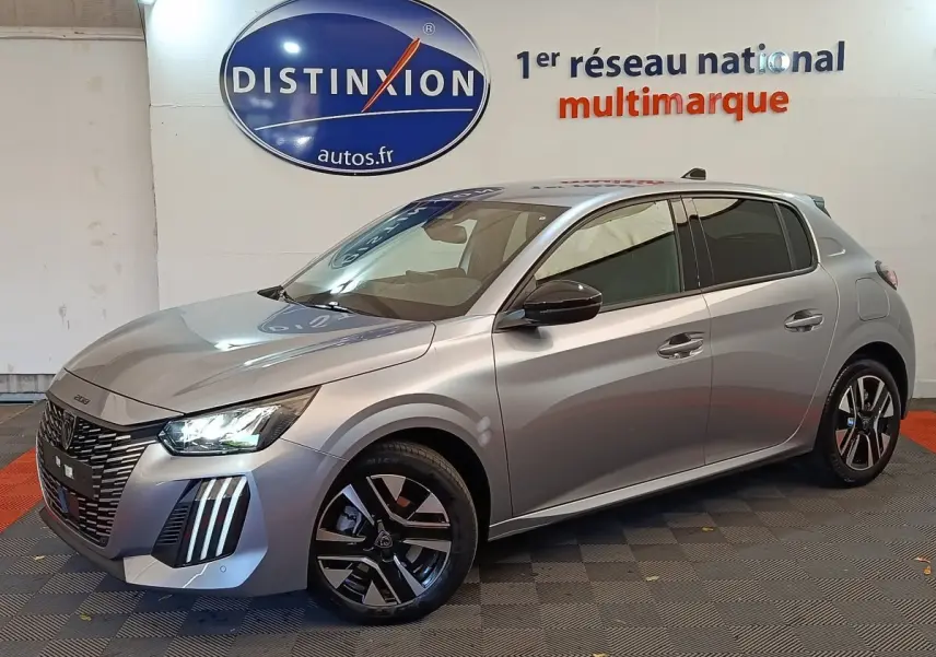 Peugeot 208 gris clair vue 3/4 avant droit, avec feux LED et jantes alliage distinctives.