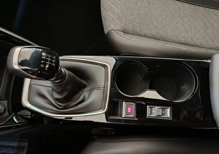 Gros plan sur la console centrale noire avec levier de vitesse manuel et accoudoir du Peugeot 208 gris clair.