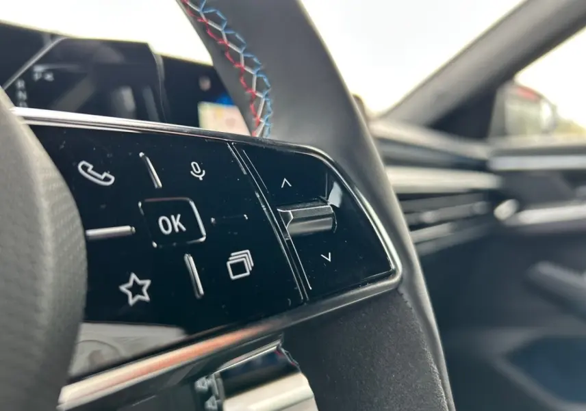 Gros plan sur les commandes du volant noir avec surpiqûres tricolores du Renault Rafale esprit Alpine hybride 2025.