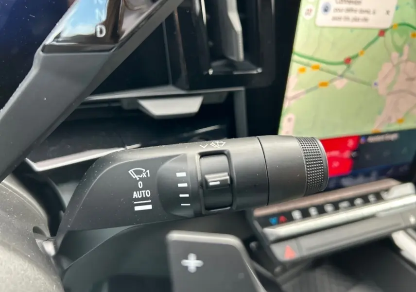 Gros plan sur la commande d'essuie-glace à gauche du volant du Renault Rafale noir, avec écran tactile de navigation visible.