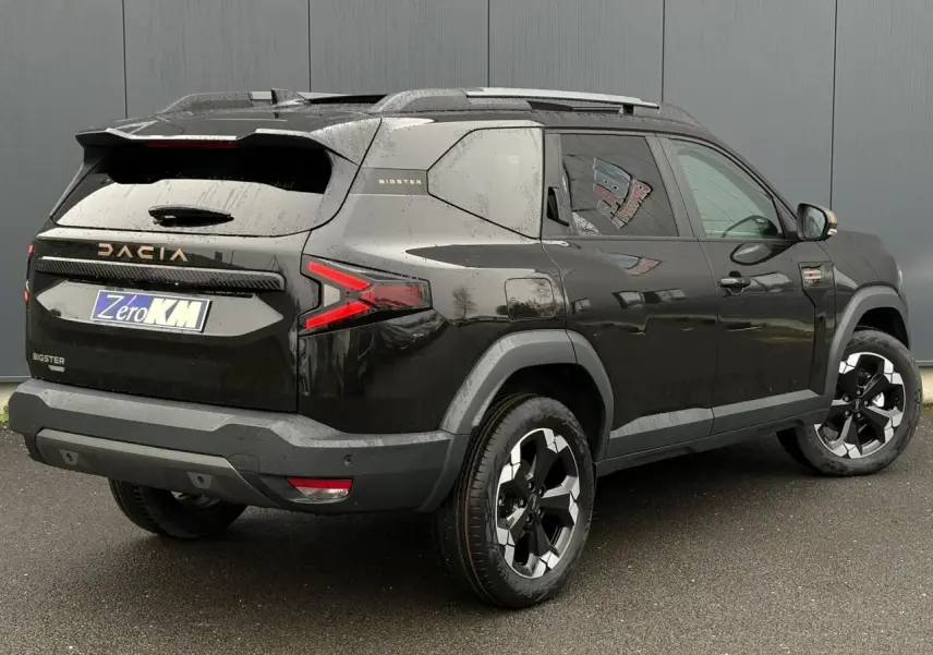 Vue 3/4 arrière droite du Dacia Bigster noir nacré avec jantes alliage et hayon électrique visible.