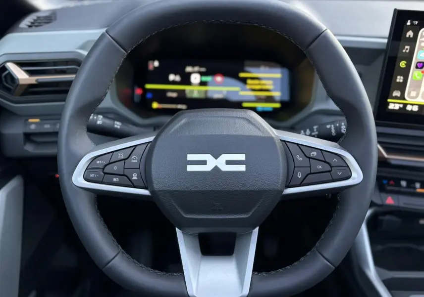 Vue rapprochée du volant multifonction noir du Dacia Bigster 2026 avec tableau de bord numérique en arrière-plan.