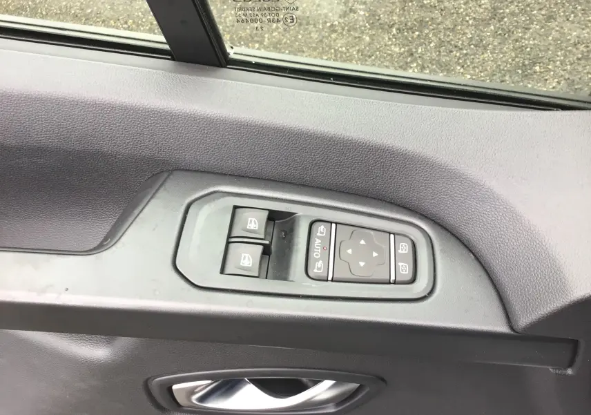 Gros plan sur les commandes des vitres électriques et des rétroviseurs côté conducteur du Renault Trafic blanc 2023.