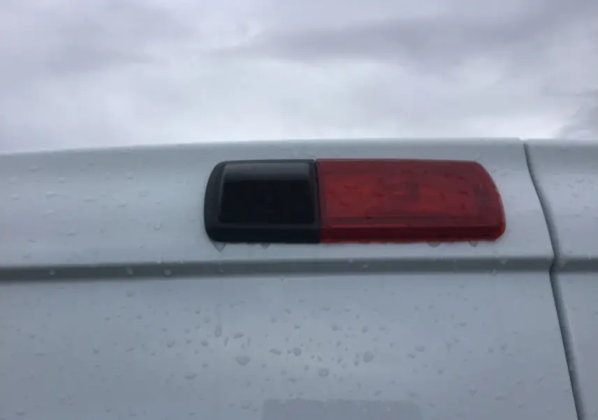 Gros plan sur la caméra de recul intégrée au feu arrière rouge du Renault Trafic Fourgon blanc 2023.