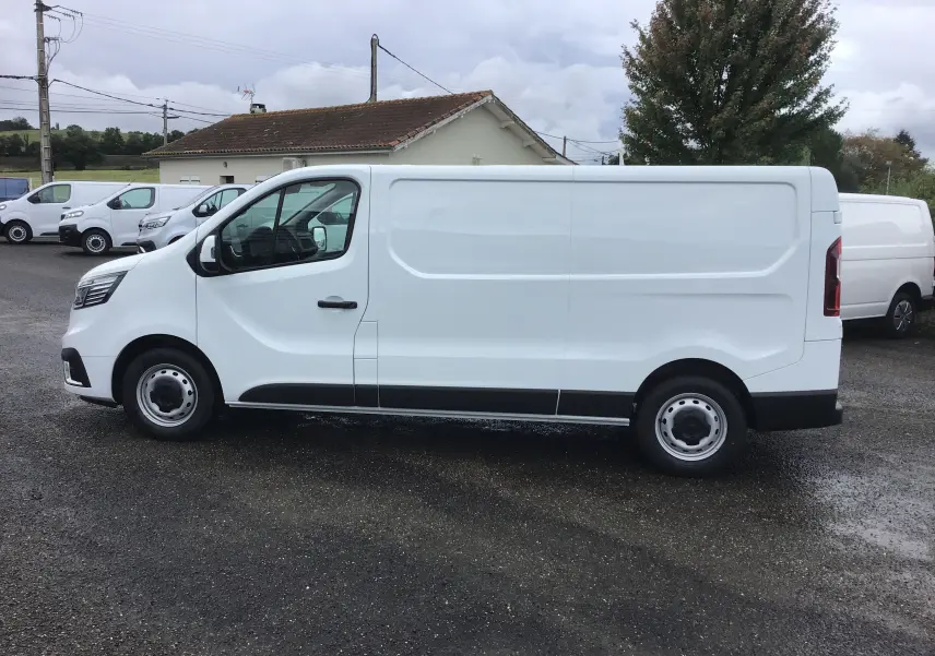 Renault Trafic Fourgon blanc vu de profil côté gauche, avec porte latérale coulissante et jantes acier simples.