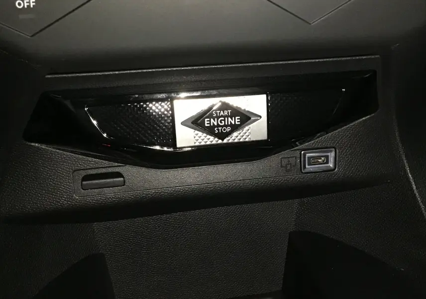 Bouton Start Engine Stop en gros plan sur la console noire intérieure du DS3 Crossback gris platinium 2024.