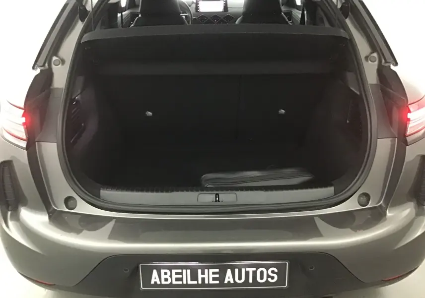 Coffre ouvert vu de l'arrière d'un DS3 Crossback gris platinium 2024, intérieur noir et feux arrière allumés.