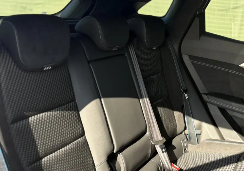 Vue intérieure des sièges arrière noirs du Renault Austral E-Tech, avec appuie-têtes et ceintures visibles côté droit.