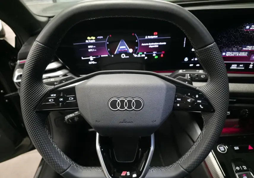 Volant sport en cuir avec commandes multifonctions et logo S de l'Audi A5 Avant noir, vue centrée depuis le siège conducteur.