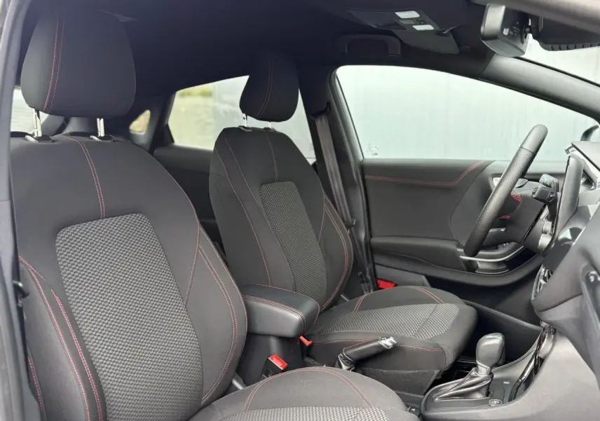 Intérieur avant de la Ford Puma gris Solar, sièges noirs avec surpiqûres rouges et volant ST-Line visible côté droit.