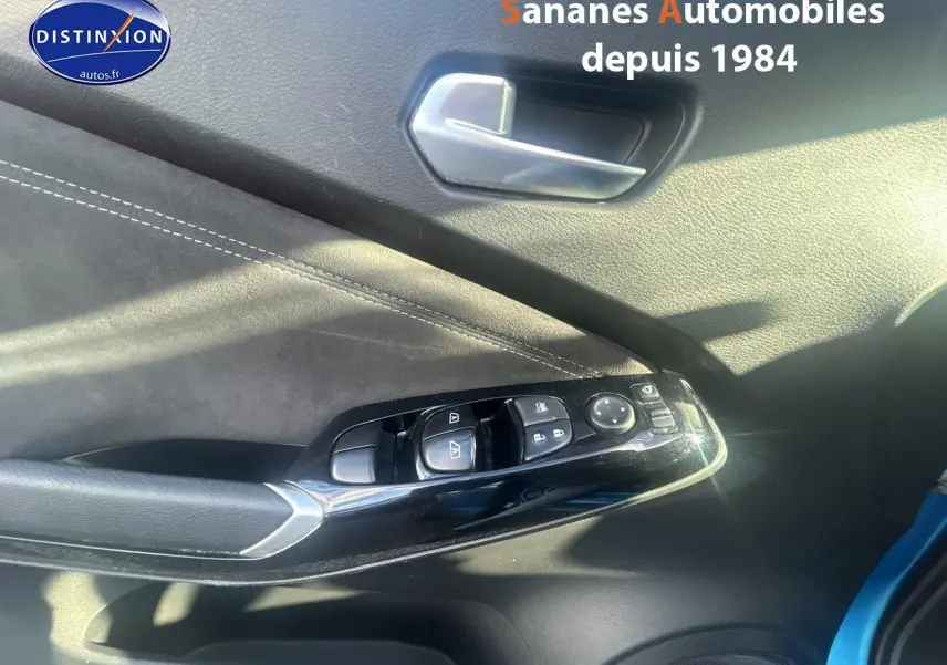 Détail des commandes de lève-vitres et rétroviseurs sur la porte avant gauche d’un Nissan Juke bleu clair 2020.