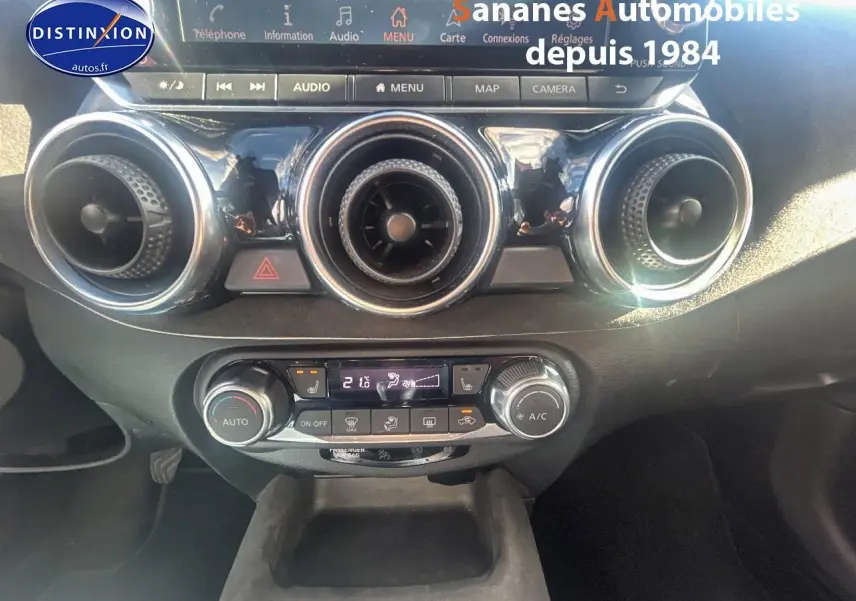 Vue rapprochée du tableau de bord du Nissan Juke 2020, mettant en valeur les commandes de climatisation et les aérateurs ronds.