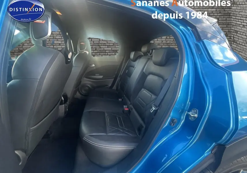 Vue côté droit arrière du Nissan Juke bleu clair 2020, montrant les sièges arrière en cuir noir et l'ouverture de porte.