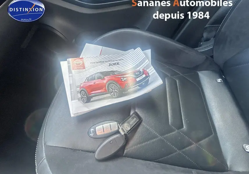 Gros plan sur le siège avant droit en cuir noir avec clé Nissan et brochure du Juke posées dessus.