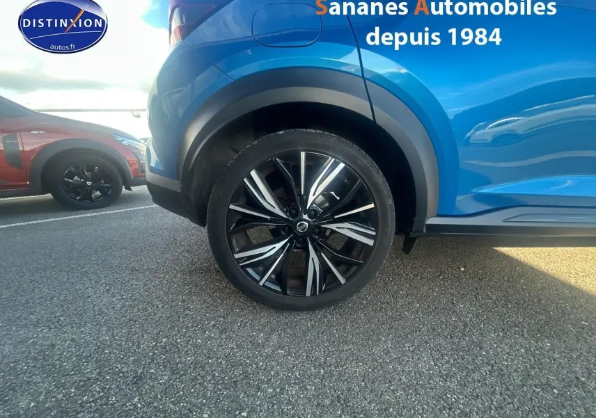 Gros plan sur la roue arrière droite d’un Nissan Juke bleu clair 2020 avec jante alliage noire et argentée.