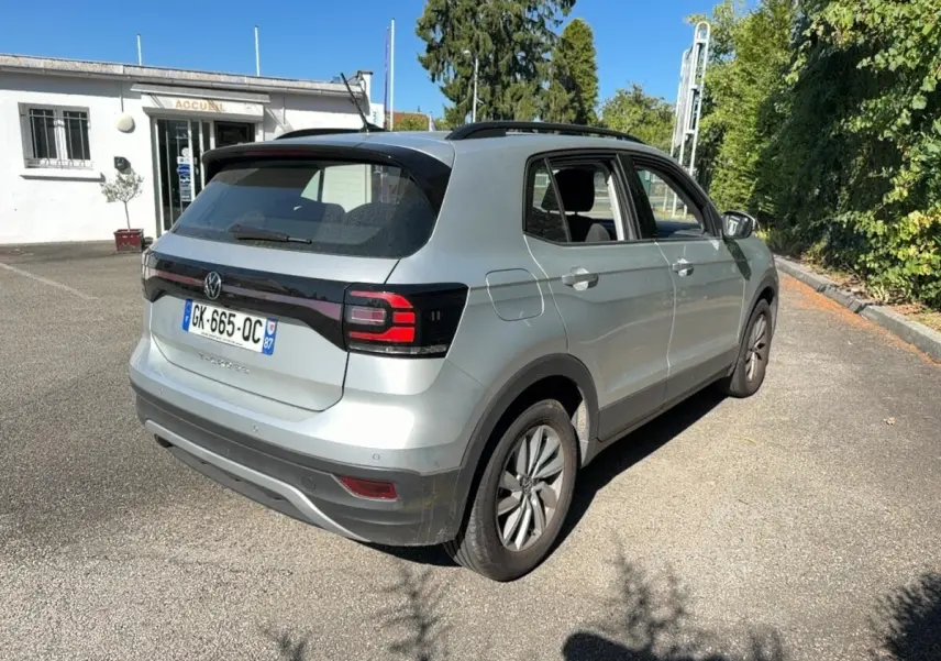 Volkswagen T-Cross gris clair vu en 3/4 arrière droit, avec feux arrière LED et toit noir contrasté.