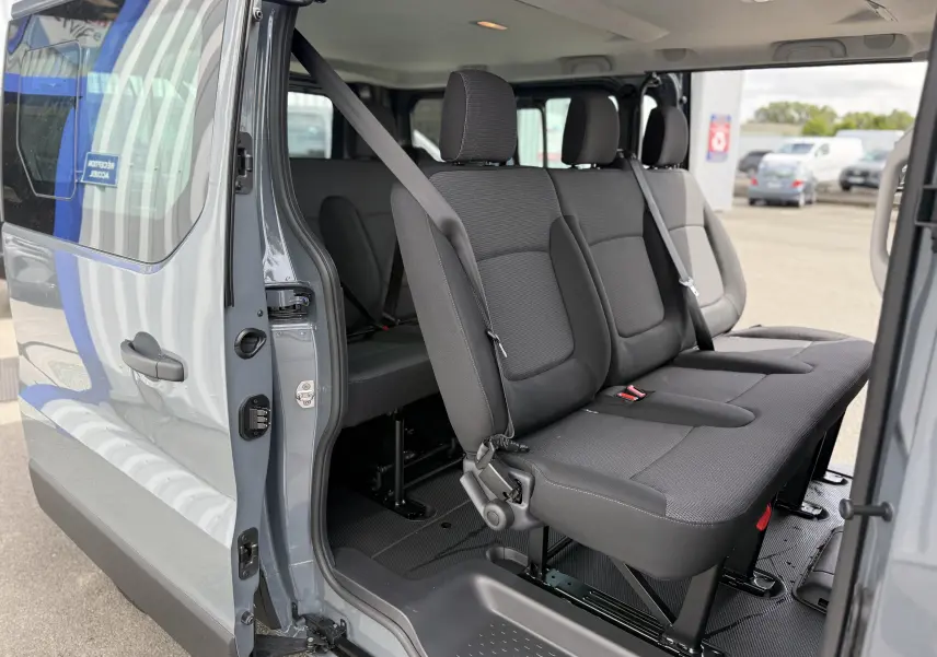 Vue intérieure côté droit du Renault Trafic Combi gris Urban 2025, montrant les sièges passagers en tissu noir.
