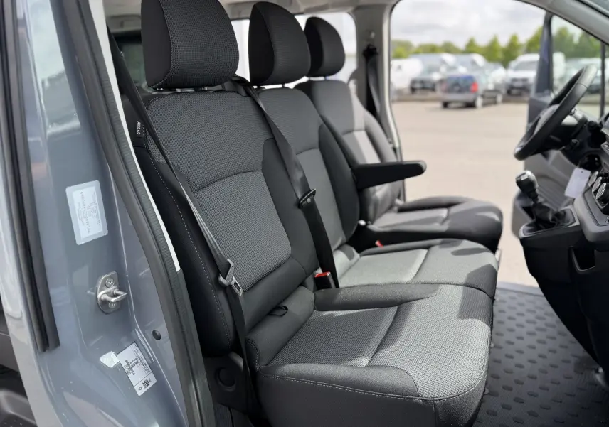 Intérieur côté conducteur du Renault Trafic Combi gris urban 2025, siège avant 3 places avec accoudoir central.