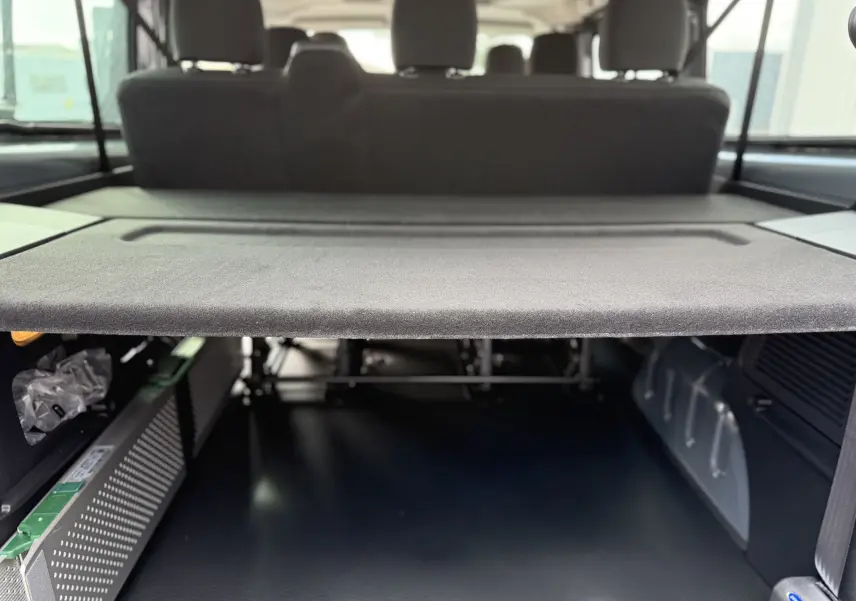 Vue intérieure du coffre du Renault Trafic Combi gris Urban 2025, montrant la tablette arrière et les sièges arrière.