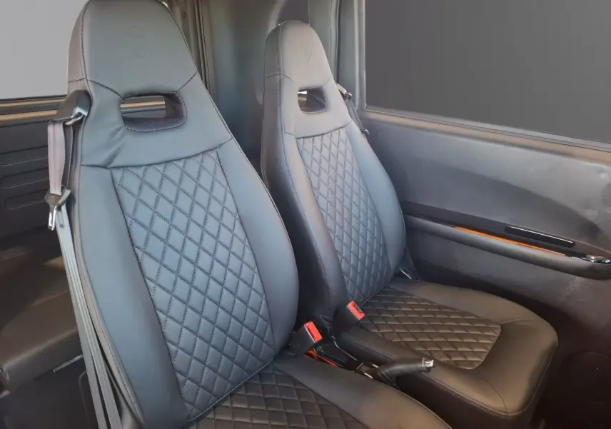 Vue intérieure des sièges avant en cuir noir matelassé du Simplici S1 gris perle avec détails de la portière côté droit.