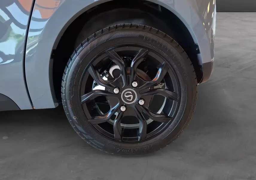 Gros plan sur la roue arrière droite noire à jante stylisée du SIMPLICI S1 gris perle avec toit noir.