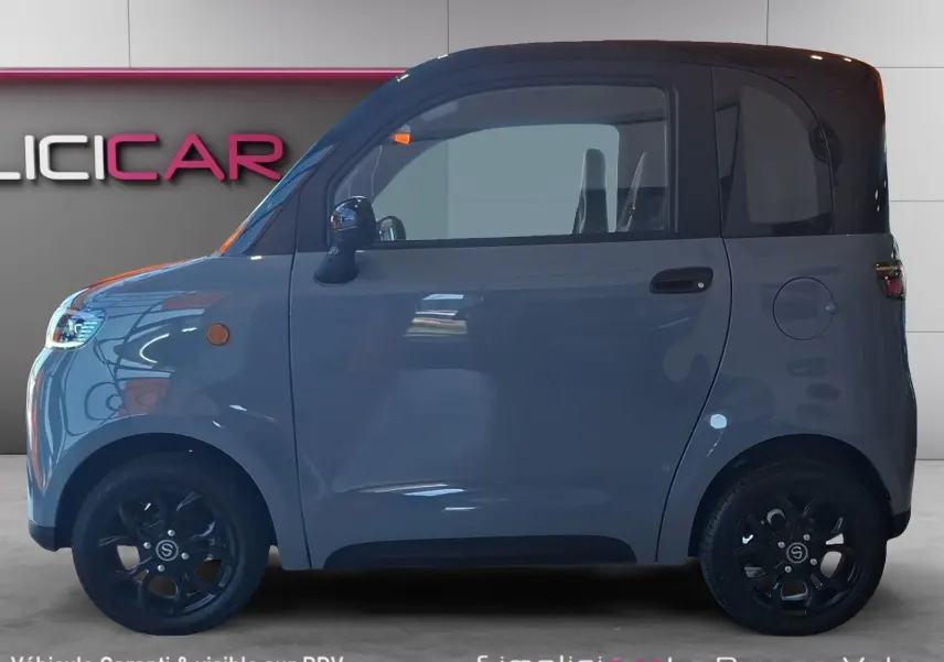 Vue de profil côté gauche d'une Simplici S1 électrique gris perle avec toit noir et jantes noires compactes.