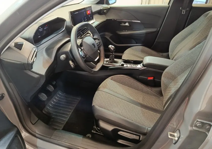 Intérieur avant droit de la Peugeot 208 gris foncé, avec tableau de bord numérique et volant cuir multifonctions.