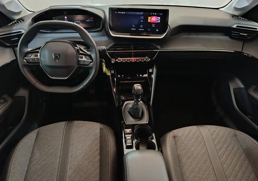 Intérieur avant de la Peugeot 208 gris foncé, vue du tableau de bord avec volant cuir et écran tactile central.