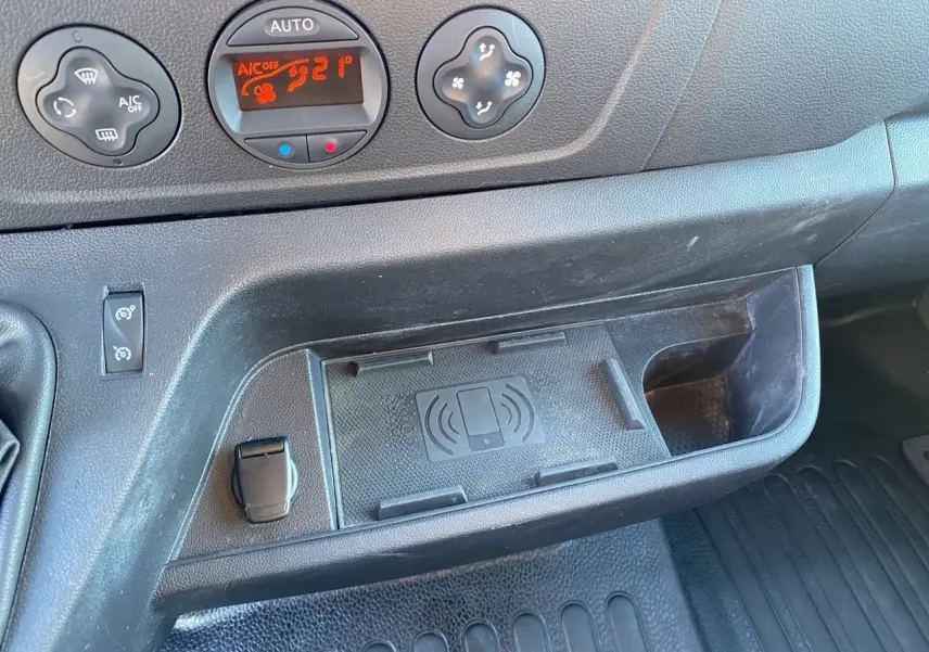 Détail de la console centrale noire du Nissan Interstar 2022 avec commandes de climatisation digitale et espace de recharge sans fil.