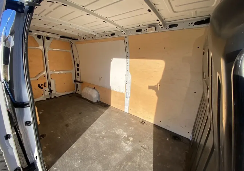 Vue intérieure de la zone de chargement du fourgon blanc Nissan Interstar L3H2, avec parois et sol protégés par un revêtement bois.