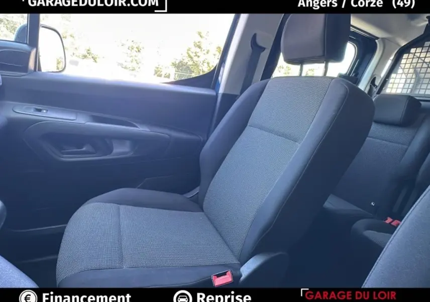 Intérieur du Peugeot Rifter 2024, siège avant droit en tissu gris et noir, vue côté passager avec porte et fenêtre visibles.