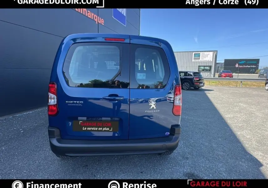 Vue arrière d'un Peugeot Rifter bleu 2024 avec portes battantes et logo Peugeot visible, stationné en extérieur.
