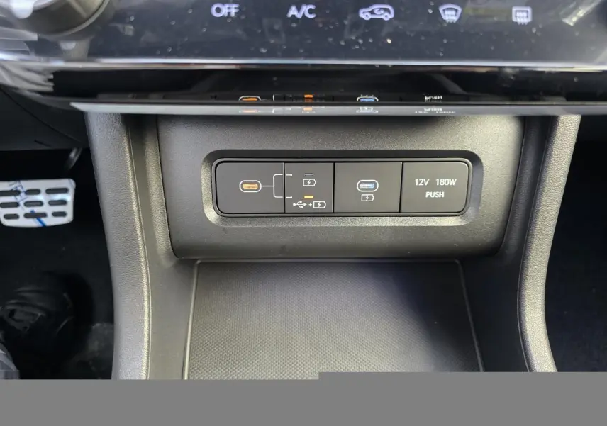 Gros plan sur la console centrale du Hyundai Tucson 2025, montrant prises USB-C et prise 12V, finition noire.