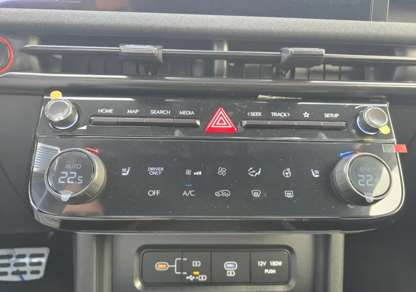 Vue rapprochée de la console centrale noire du Hyundai Tucson 2025, avec commandes climatisation et boutons multimédia.