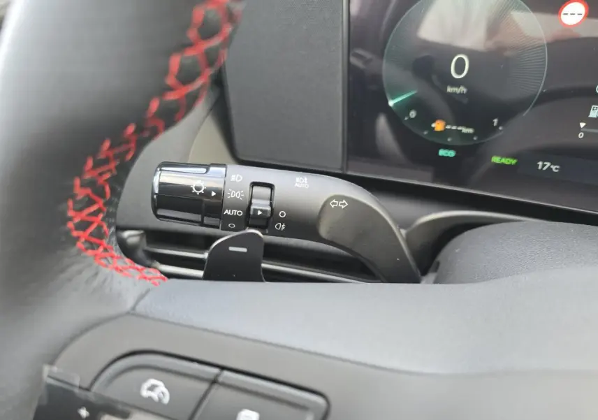 Gros plan sur la manette des feux et clignotants du Hyundai Tucson N Line 2025, volant cuir noir à surpiqûres rouges visible.