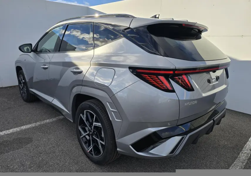 Vue 3/4 arrière droite du Hyundai Tucson 2025 hybride en gris métallisé avec feux arrière LED et jantes alliage 19 pouces N Line.