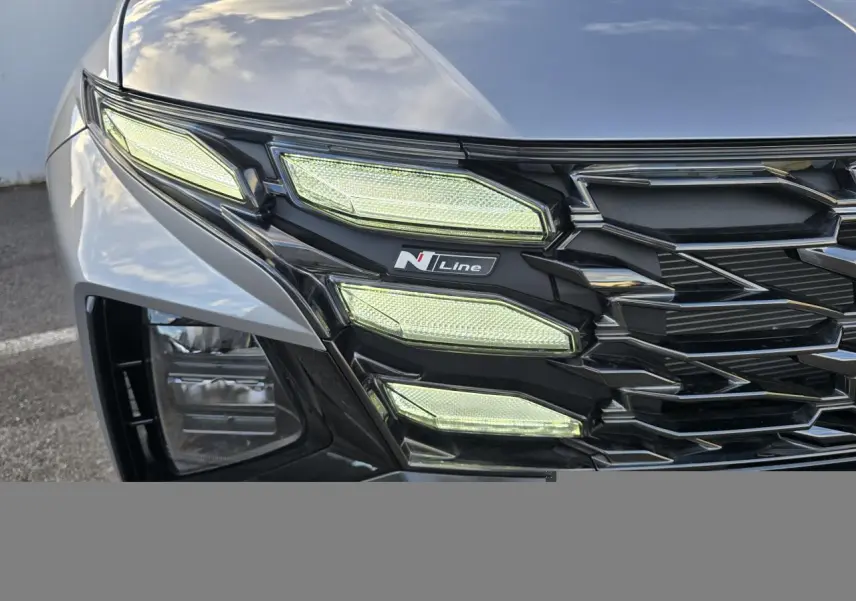 Gros plan sur le phare avant gauche du Hyundai Tucson 2025 Shimmering Silver avec logo N Line et calandre noire.