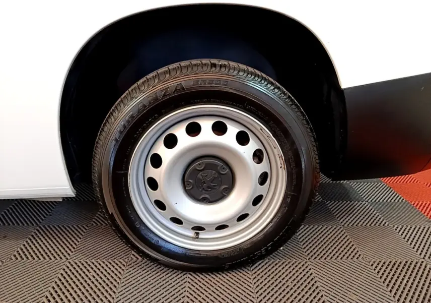 Gros plan sur la roue arrière droite en jante acier du Peugeot Partner blanc, avec partie basse de la carrosserie visible.