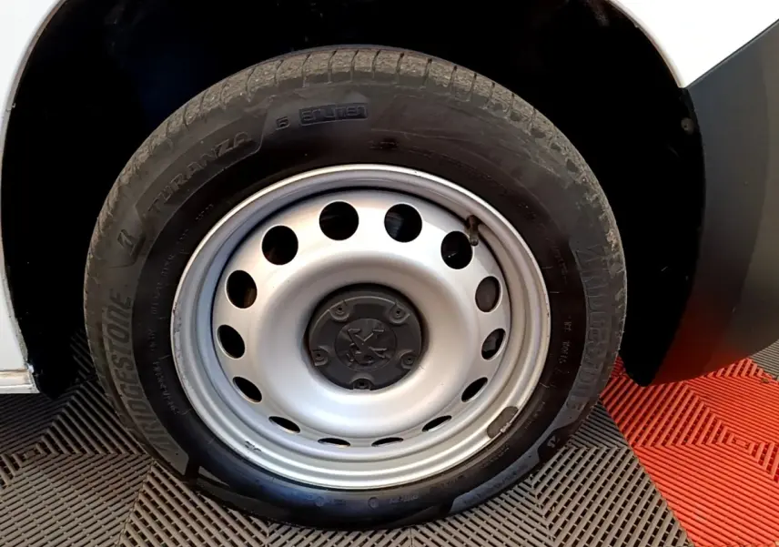 Gros plan sur la roue avant droite en jante acier du Peugeot Partner blanc, avec pneu Bridgestone.