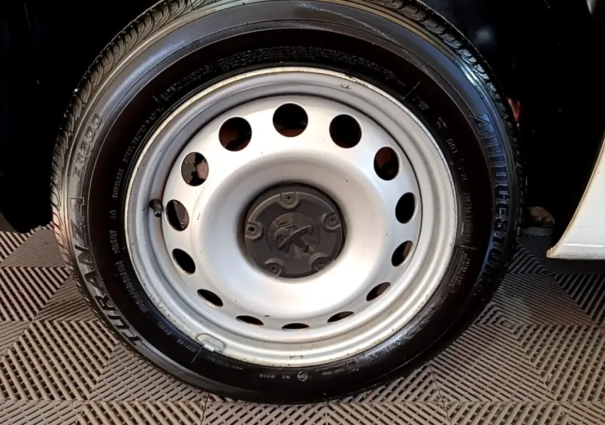 Gros plan sur la roue acier blanche avec logo Peugeot d’un Peugeot Partner blanc, vue côté droit.