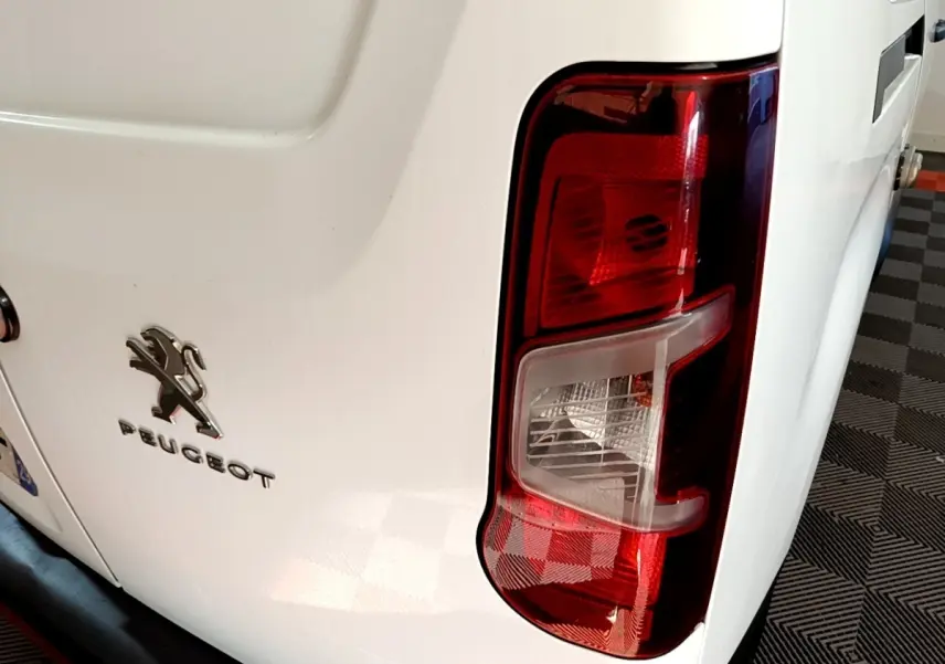 Vue rapprochée arrière droite du Peugeot Partner blanc, mettant en valeur le feu arrière et le logo Peugeot.
