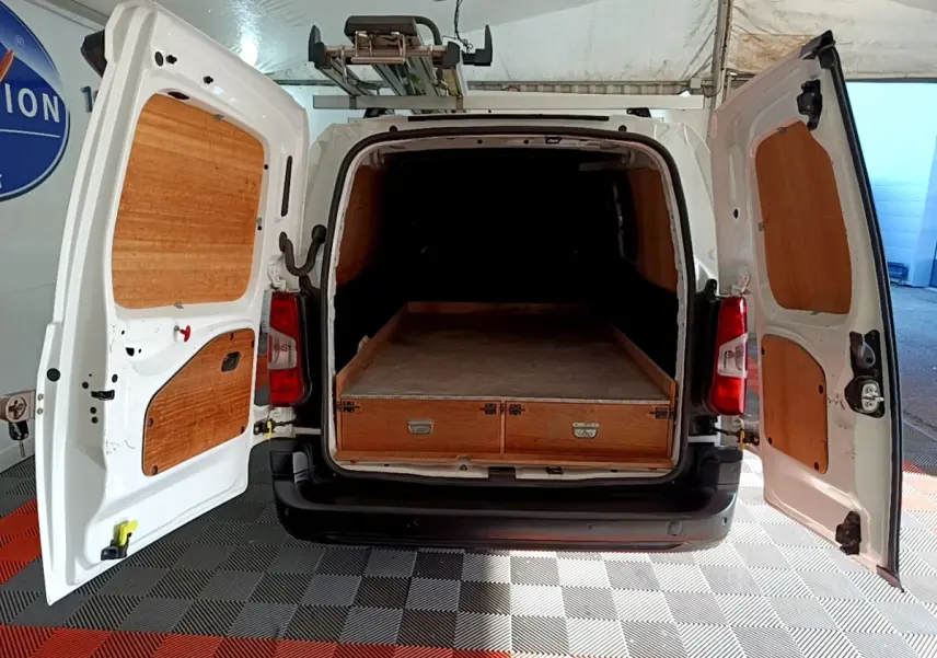 Vue arrière du Peugeot Partner blanc 2021 avec portes ouvertes et aménagement bois dans l’espace de chargement.