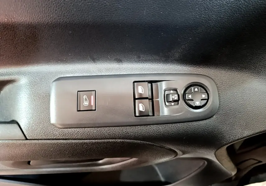 Gros plan sur les commandes de lève-vitres et réglage des rétroviseurs sur la porte intérieure noire d’un Peugeot Partner blanc.
