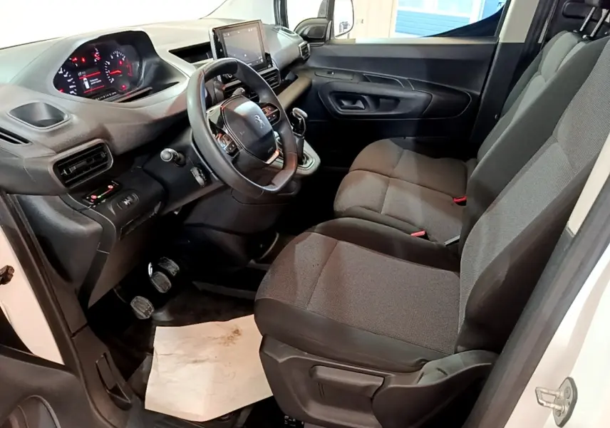 Intérieur avant droit du Peugeot Partner blanc 2021, montrant sièges tissu gris et tableau de bord avec écran tactile.