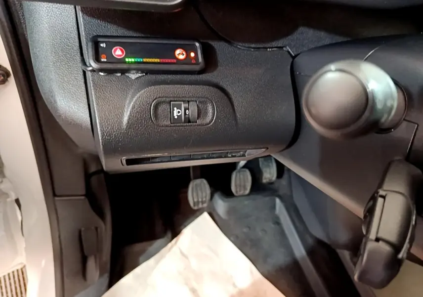 Vue intérieure côté conducteur du Peugeot Partner blanc 2021, montrant les pédales et commandes sous le tableau de bord.