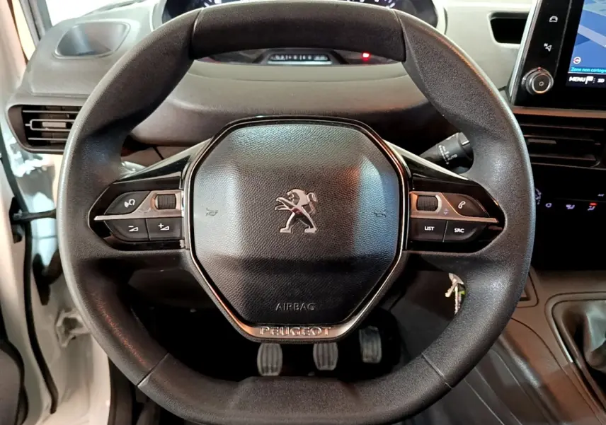 Vue rapprochée du volant noir du Peugeot Partner blanc 2021 avec commandes intégrées et tableau de bord tactile.