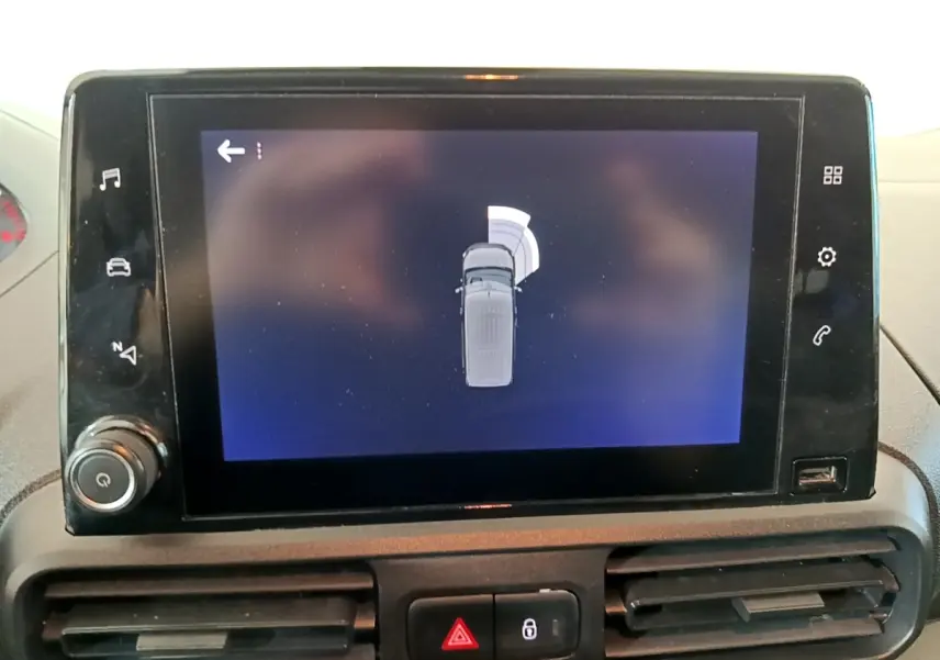 Écran tactile central montrant l'aide au stationnement du Peugeot Partner blanc, vue intérieure du tableau de bord.