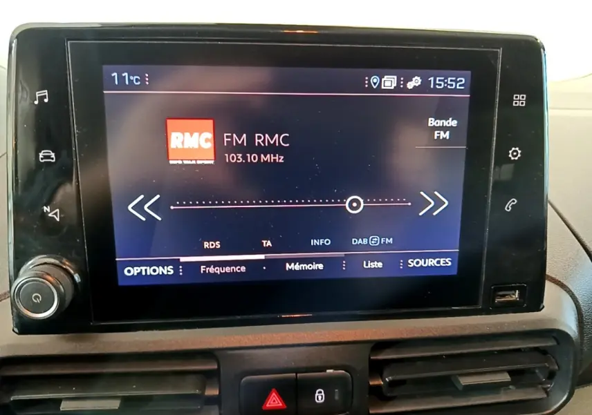Écran tactile central du tableau de bord du Peugeot Partner blanc, affichant la radio FM RMC à 103,10 MHz.