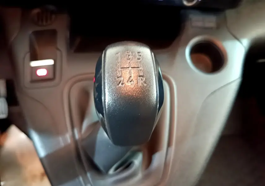 Gros plan sur le levier de vitesses manuel noir du Peugeot Partner 2021, avec console centrale beige en arrière-plan.