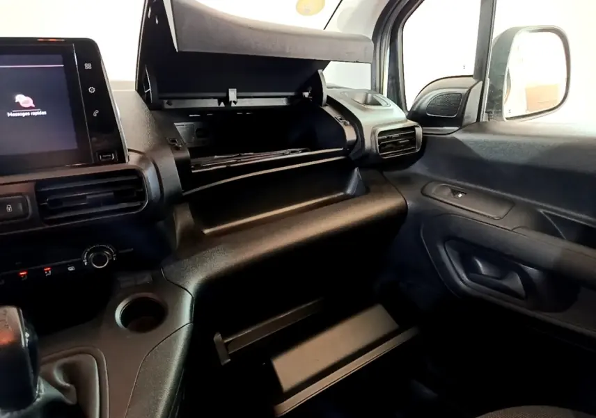 Vue intérieure côté passager du Peugeot Partner 2021, tableau de bord noir avec boîte à gants ouverte et écran tactile visible.